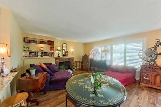 living room with a brick fireplace and wood finished floors