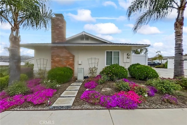 bungalow-style home featuring a chimney and stucco siding