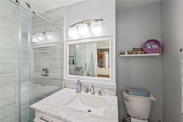 bathroom with toilet, a shower stall, and vanity