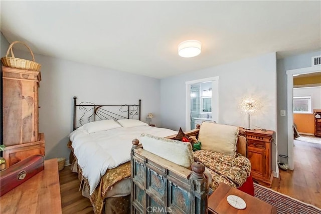 bedroom with wood finished floors and connected bathroom