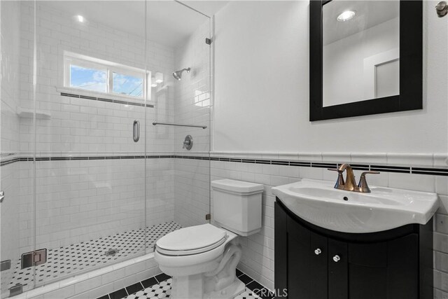 561 S Ventu Park Rd, Newbury Park, CA 91320 - bathroom with vanity, a shower stall, wainscoting, tile walls, and tile patterned floors