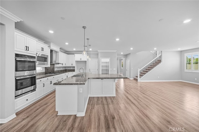 33378 Barmetta Ln, Temecula, CA 92592 - kitchen featuring appliances with stainless steel finishes, light wood-style floors, decorative backsplash, a kitchen island with sink, and open floor plan