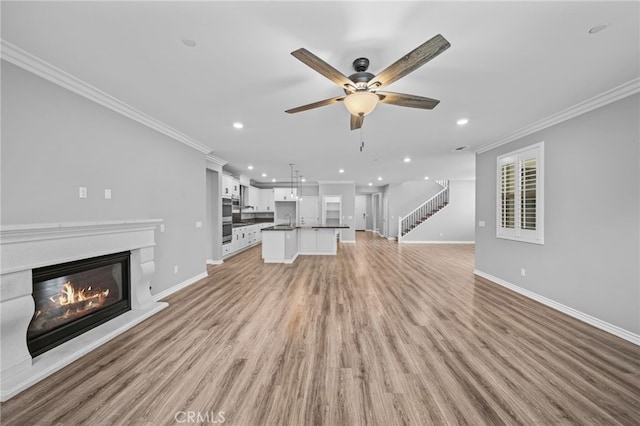 33378 Barmetta Ln, Temecula, CA 92592 - unfurnished living room featuring crown molding, recessed lighting, a glass covered fireplace, ceiling fan, and baseboards