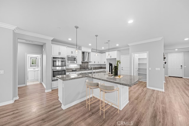 33378 Barmetta Ln, Temecula, CA 92592 - kitchen featuring stainless steel appliances, wall chimney exhaust hood, white cabinets, a kitchen island with sink, and tasteful backsplash