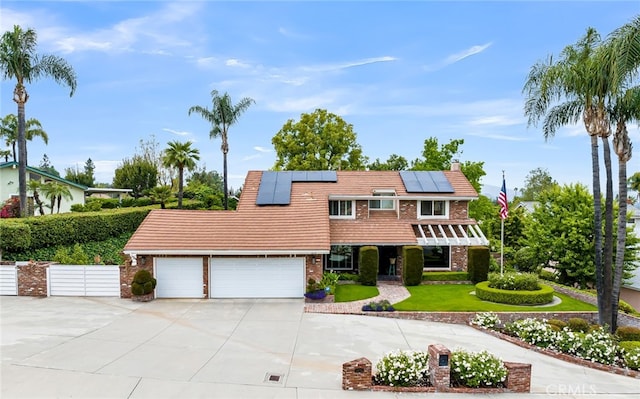 1475 Trenton Dr, Riverside, CA 92506 - view of front of property with driveway, an attached garage, roof mounted solar panels, brick siding, and a chimney