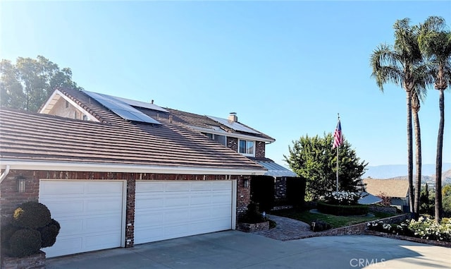 1475 Trenton Dr, Riverside, CA 92506 - view of property exterior with solar panels, an attached garage, driveway, and a tile roof