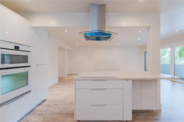 8963 Burton Way Unit 103, Los Angeles, CA 90048 - kitchen featuring modern cabinets, island range hood, white double oven, cooktop, and recessed lighting
