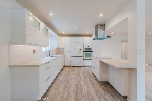 kitchen with modern cabinets, white appliances, extractor fan, light wood-type flooring, and white cabinetry