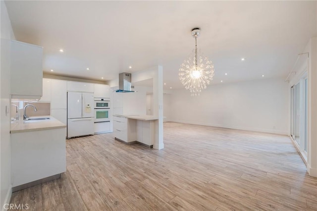8963 Burton Way Unit 103, Los Angeles, CA 90048 - kitchen featuring white appliances, a sink, wall chimney exhaust hood, light countertops, and recessed lighting