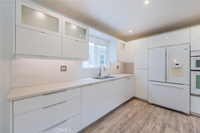 8963 Burton Way Unit 103, Los Angeles, CA 90048 - kitchen with white appliances, a sink, white cabinets, light wood-style floors, and light countertops