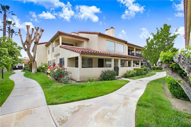 43195 Andrade Ave Unit A, Hemet, CA 92544 - back of house with a chimney, a tile roof, stucco siding, and a lawn