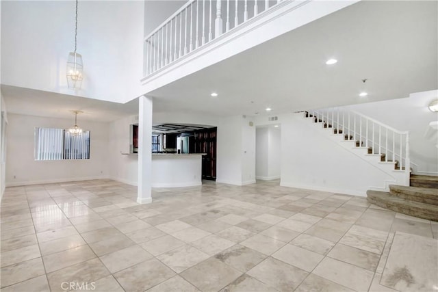 43195 Andrade Ave Unit A, Hemet, CA 92544 - unfurnished living room with a chandelier, stairway, light tile patterned floors, a high ceiling, and baseboards