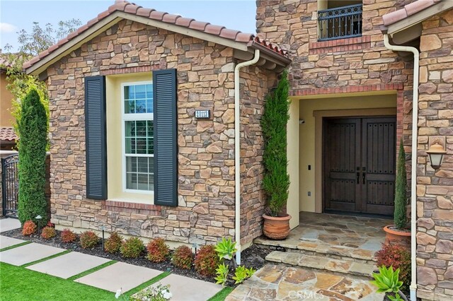 view of exterior entry featuring stone siding and a tile roof