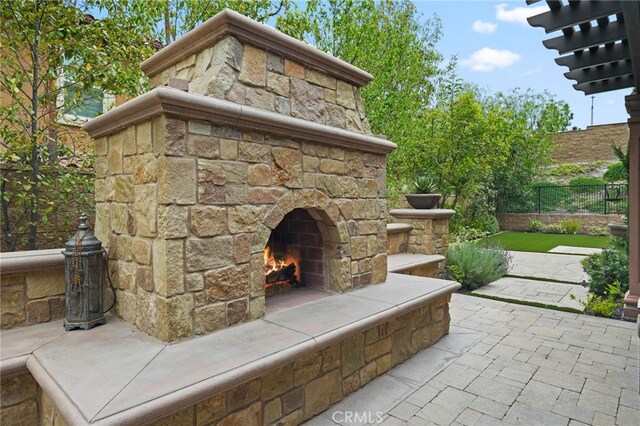 view of patio featuring an outdoor stone fireplace and fence