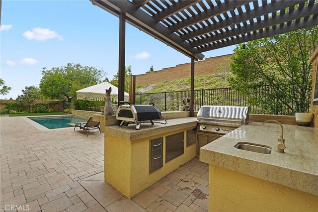 view of patio / terrace with grilling area, a sink, a fenced backyard, and exterior kitchen