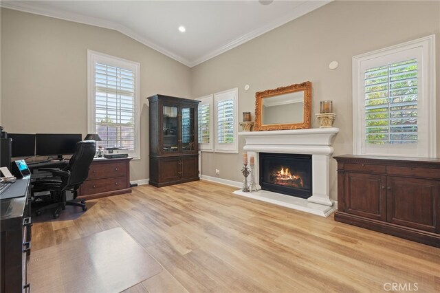 home office featuring plenty of natural light, crown molding, light wood finished floors, and a glass covered fireplace