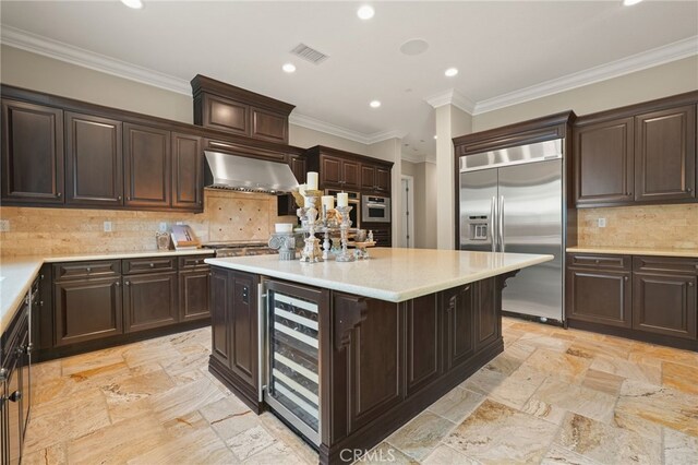 kitchen featuring built in fridge, wine cooler, recessed lighting, stone tile flooring, and light countertops