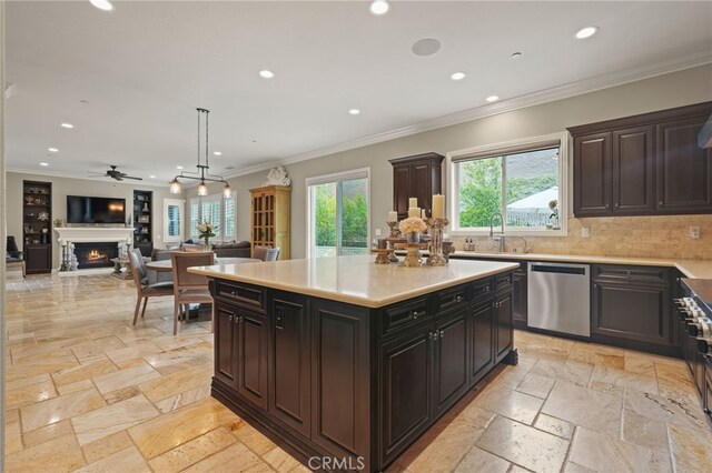 kitchen with stainless steel dishwasher, stone tile floors, recessed lighting, a warm lit fireplace, and a sink