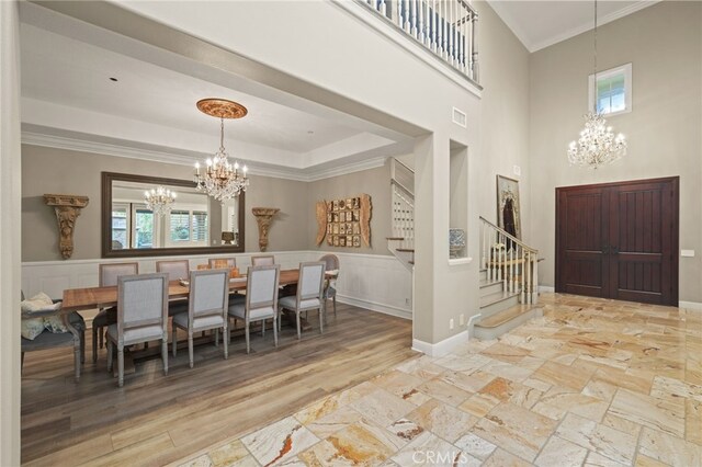 entryway with a chandelier, stairway, plenty of natural light, crown molding, and a high ceiling