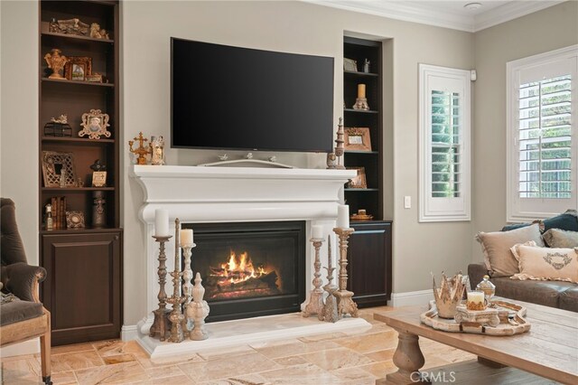 living room with built in features, ornamental molding, baseboards, and a glass covered fireplace