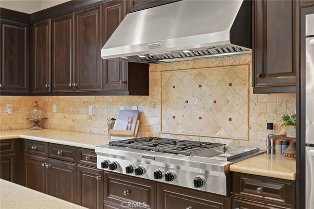 kitchen with extractor fan, stainless steel gas cooktop, dark brown cabinets, and light countertops