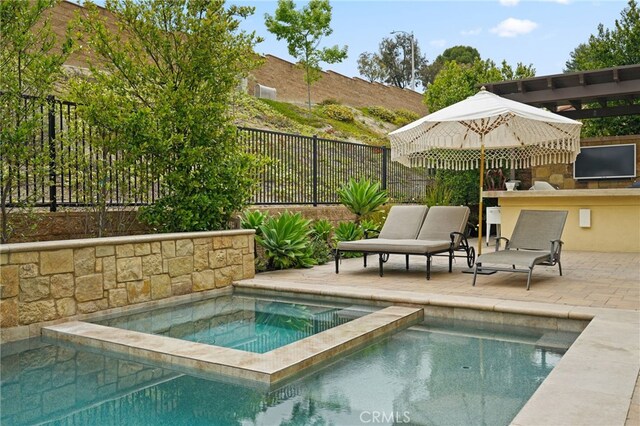 view of pool with a fenced backyard, a patio area, a pool with connected hot tub, and an outdoor kitchen
