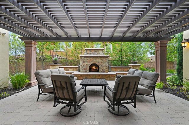 view of patio with an outdoor stone fireplace, fence, and a pergola