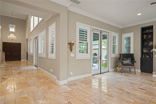 entrance foyer with stone tile flooring, a chandelier, ornamental molding, and baseboards
