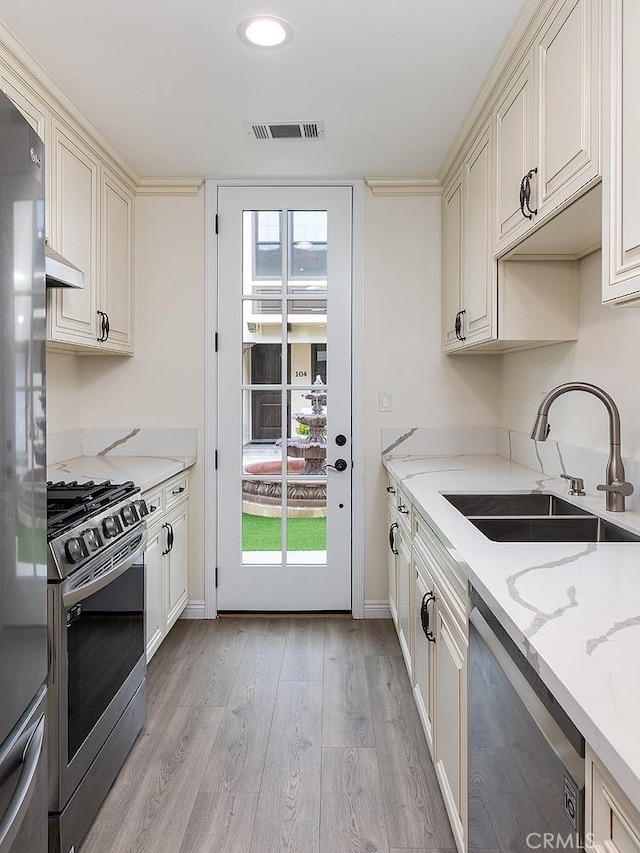 81 N Grand Oaks Ave Unit 102, Pasadena, CA 91107 - kitchen with appliances with stainless steel finishes, a sink, light wood finished floors, light stone counters, and baseboards