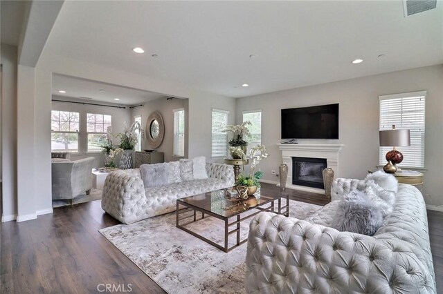 living area featuring wood finished floors, baseboards, a glass covered fireplace, and recessed lighting