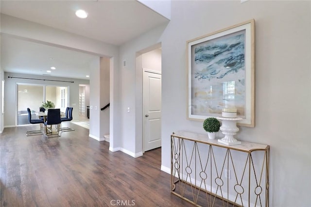 hall with wood finished floors, baseboards, recessed lighting, and stairway
