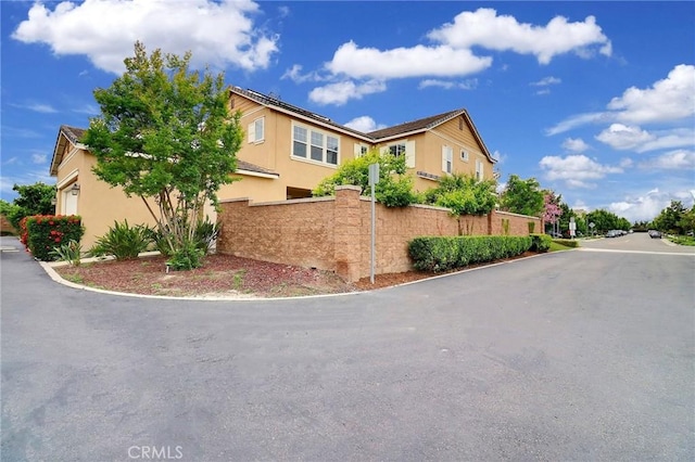 view of side of property featuring stucco siding, fence, and a garage