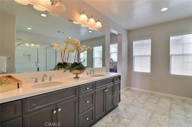 bathroom featuring a stall shower, baseboards, double vanity, and recessed lighting