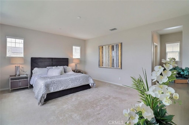 carpeted bedroom featuring multiple windows and baseboards