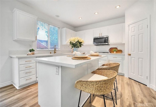 37089 Meadow Brook Way, Beaumont, CA 92223 - kitchen featuring appliances with stainless steel finishes, a sink, a kitchen island, light wood-type flooring, and light countertops
