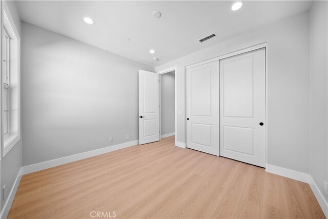 unfurnished bedroom featuring light wood-style flooring, recessed lighting, baseboards, and a closet
