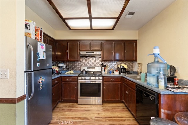 1451 Segovia Ct, Madera, CA 93638 - kitchen with appliances with stainless steel finishes, under cabinet range hood, light wood-type flooring, decorative backsplash, and a sink