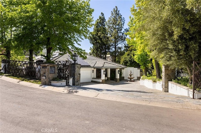 view of front of property with a garage, solar panels, and a chimney