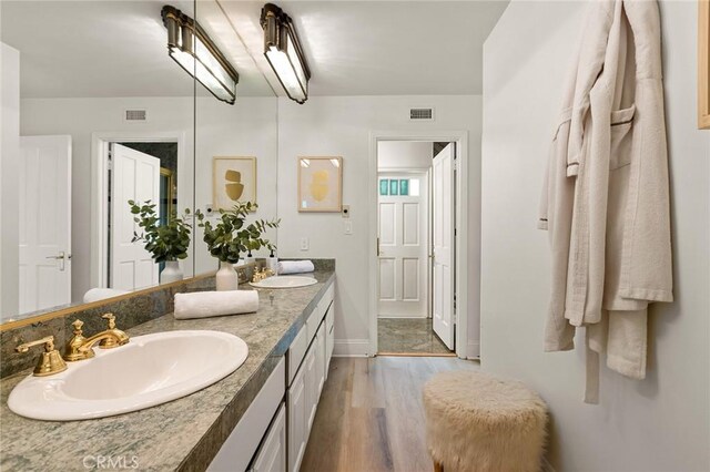 bathroom featuring wood finished floors, baseboards, and double vanity