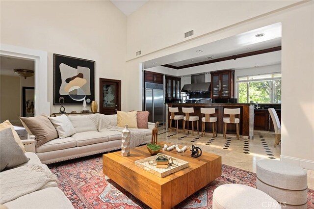 living room with bar area, baseboards, and a high ceiling