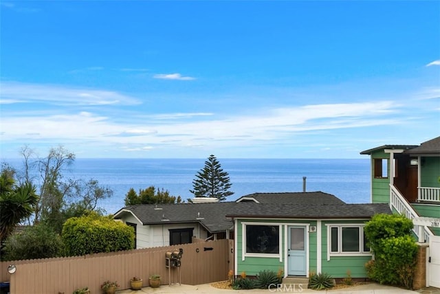 view of front of property with fence, a shingled roof, a water view, and a gate