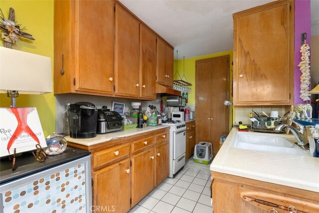 2785 Solana Way, Laguna Beach, CA 92651 - kitchen featuring white range with gas cooktop, light tile patterned flooring, a sink, and brown cabinets