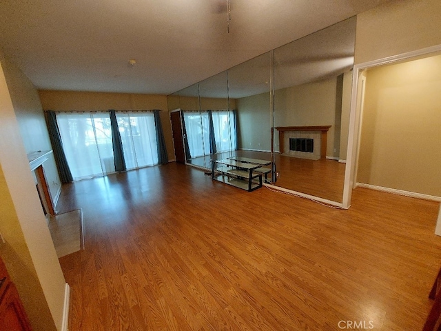 unfurnished living room with a glass covered fireplace, wood finished floors, and baseboards