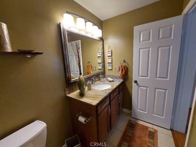 half bathroom featuring toilet, tile patterned flooring, and vanity