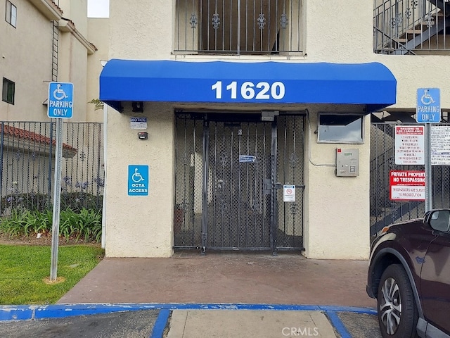 doorway to property featuring stucco siding and fence