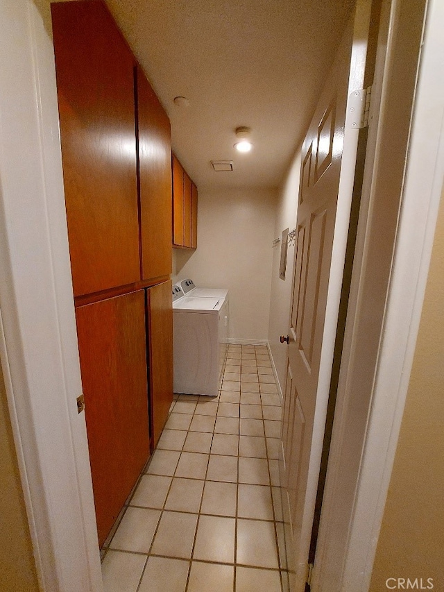 laundry room featuring washer and dryer, cabinet space, light tile patterned floors, and a textured ceiling
