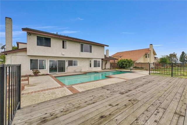 view of pool featuring a patio area, a wooden deck, and a fenced backyard