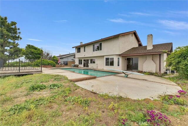 back of house featuring a patio area, a chimney, fence, and stucco siding