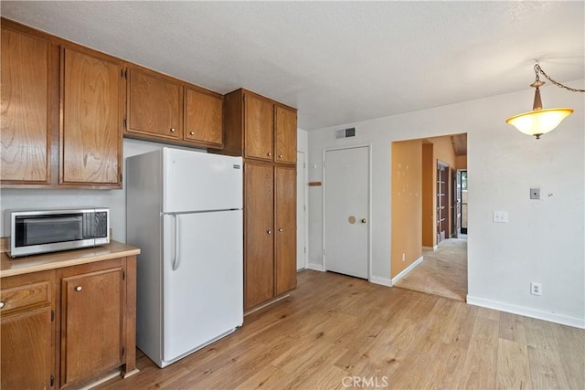 22951 Caminito Viento, Laguna Hills, CA 92653 - kitchen featuring freestanding refrigerator, stainless steel microwave, brown cabinets, and light wood-style floors