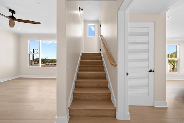stairway featuring ceiling fan, wood finished floors, ornamental molding, and baseboards
